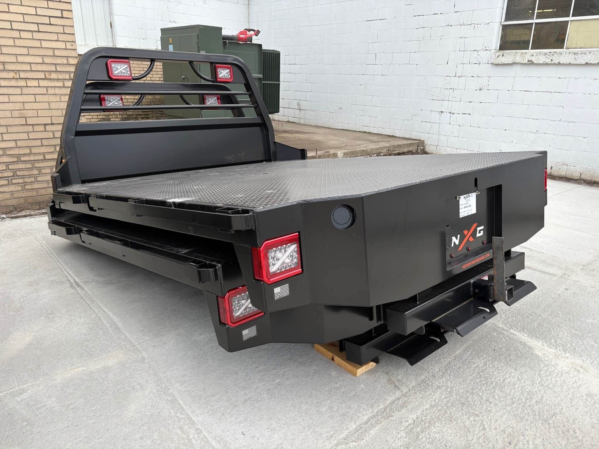 Driver-side rear angle of the NXG XFD flatbed showing the headache rack, deck, and rear bumper step
